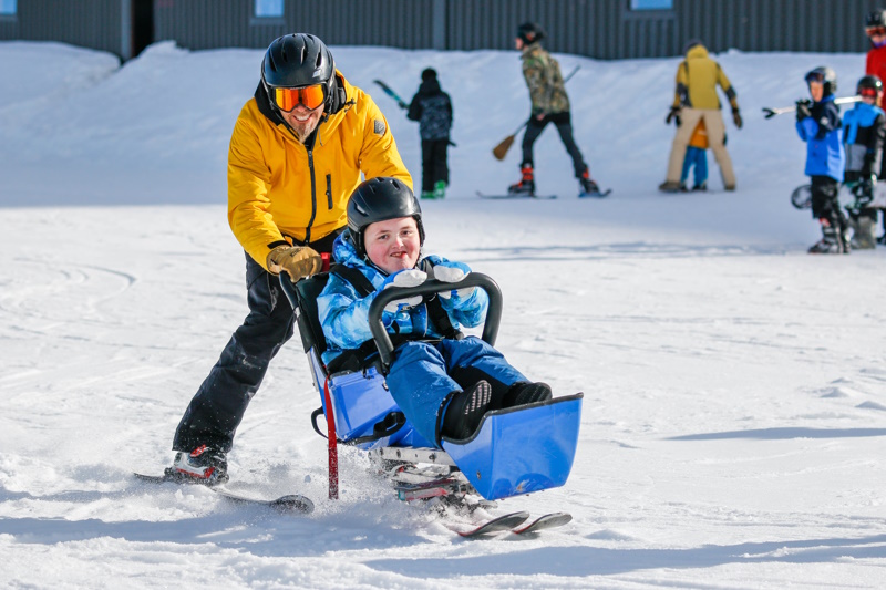 Boy enjoying a specialist ski chair in the snow.