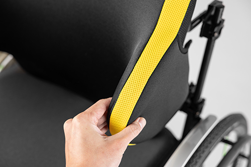 Spex Manta Back Support with yellow covers, zoomed in on the lateral wing with neoprene cover. Hand holds the wing to showcase thickness.