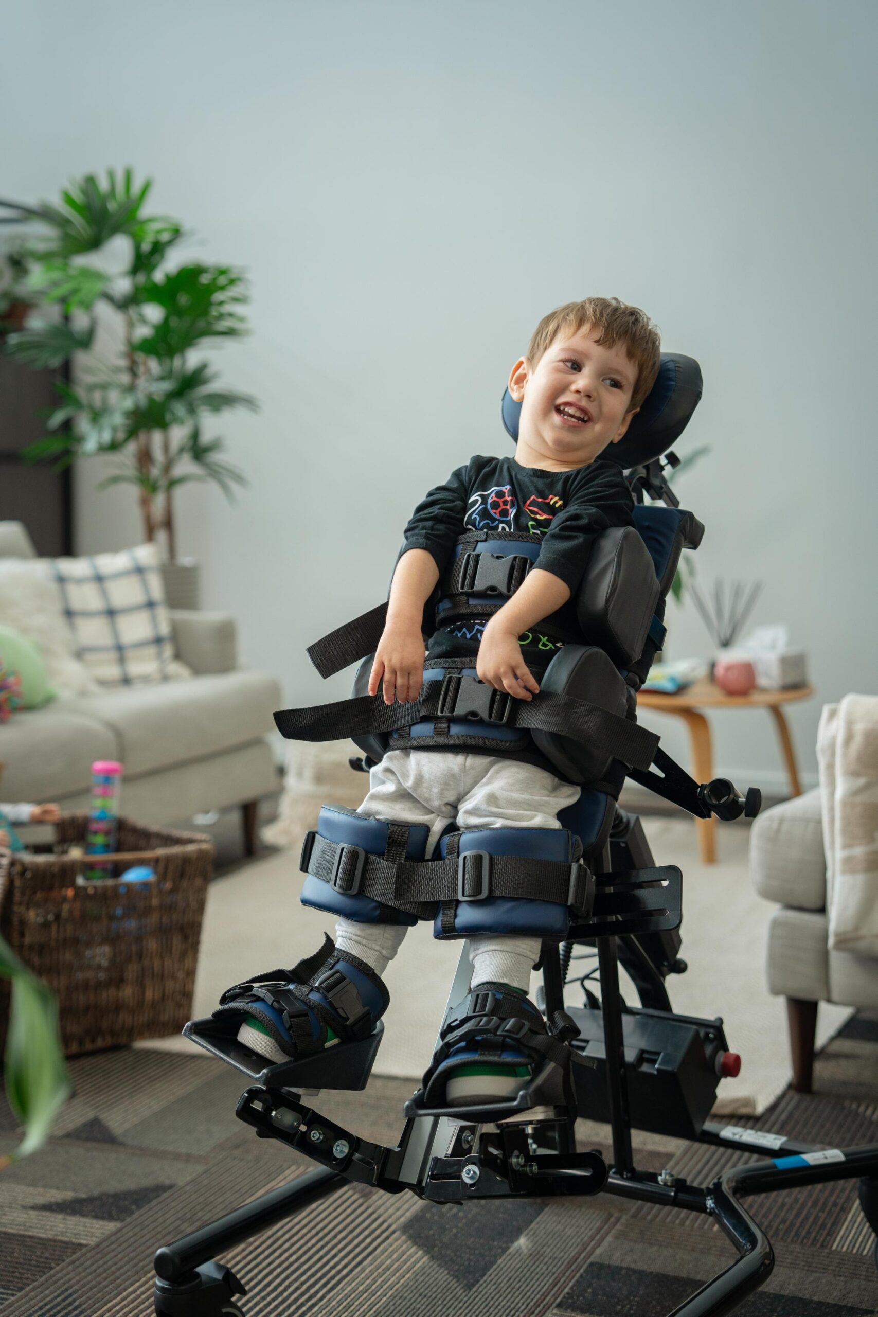 Young boy similes whilst standing in Ella Stander in a living room.