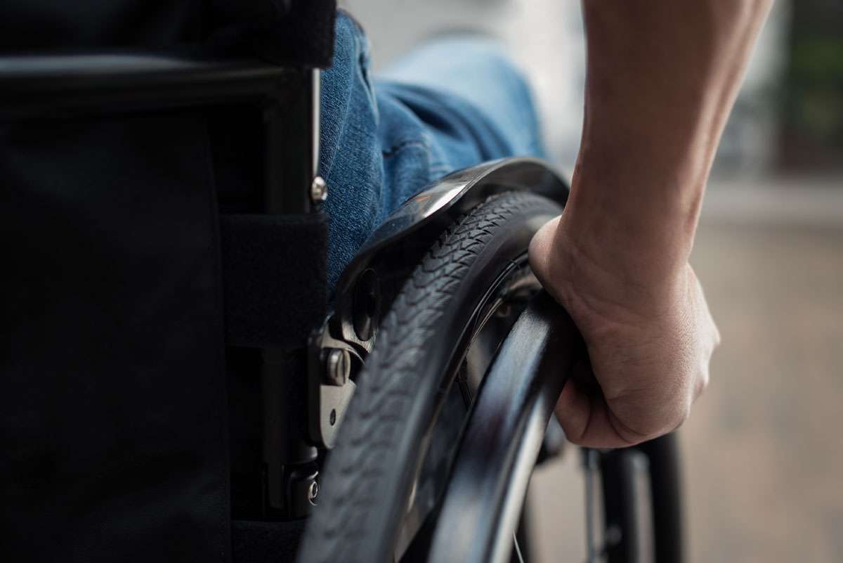 Close up image of a hand pushing a wheelchiar rim from the back.