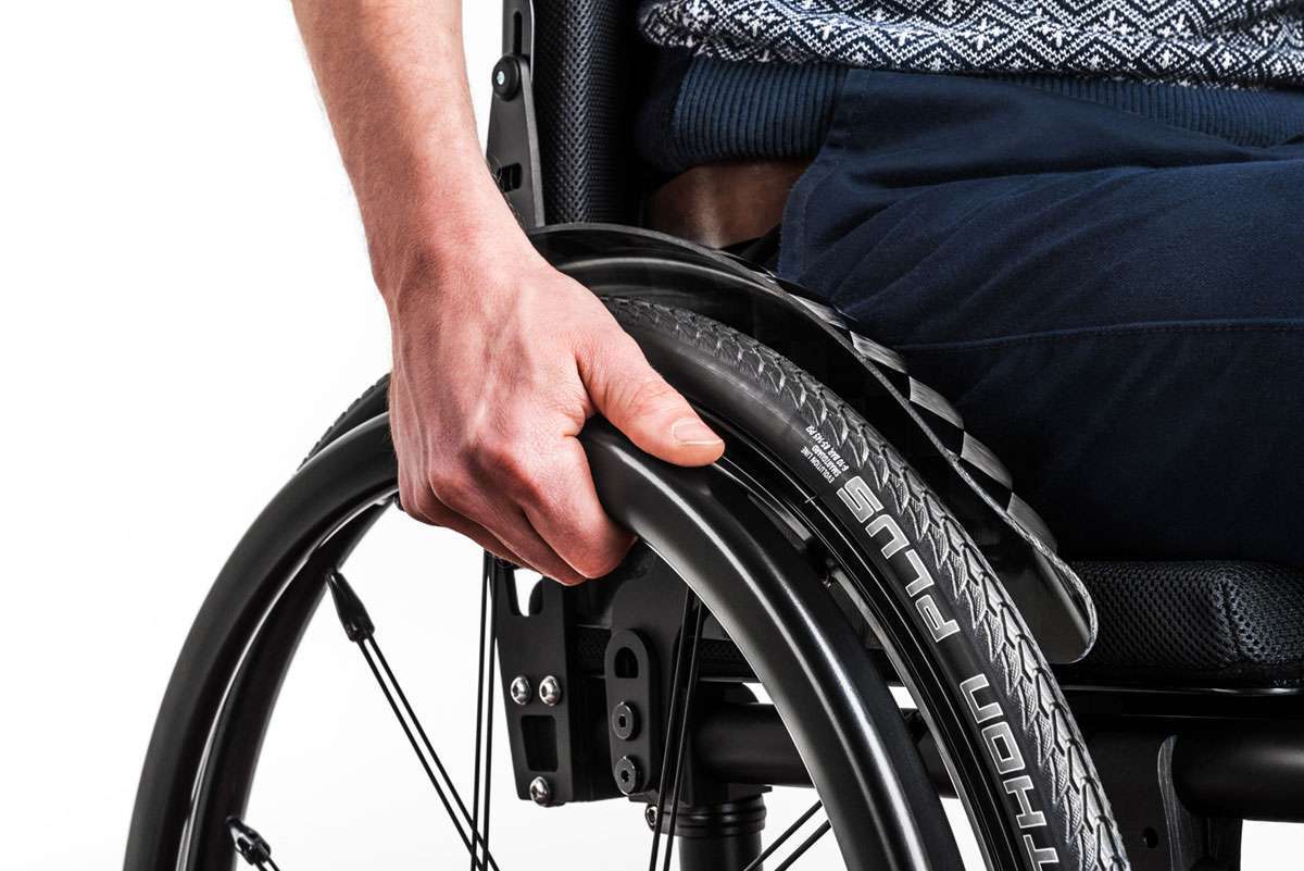 Close up image of a hand pushing a wheelchiar rim from the front.