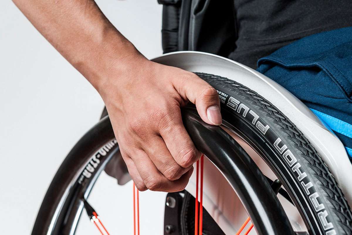 Close up image of hand pushing the wheelchair rim with wheel guard attached