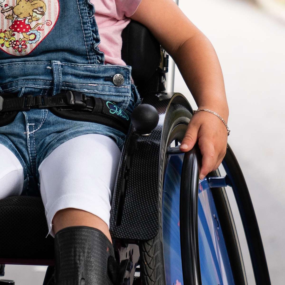 Close up image of young girl hand on a wheelchair rim.