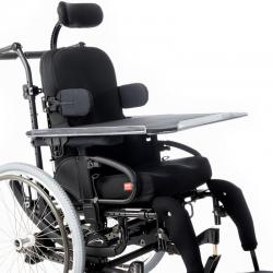 Black manual wheelchair with truck supports, an extended head support and a tray table.