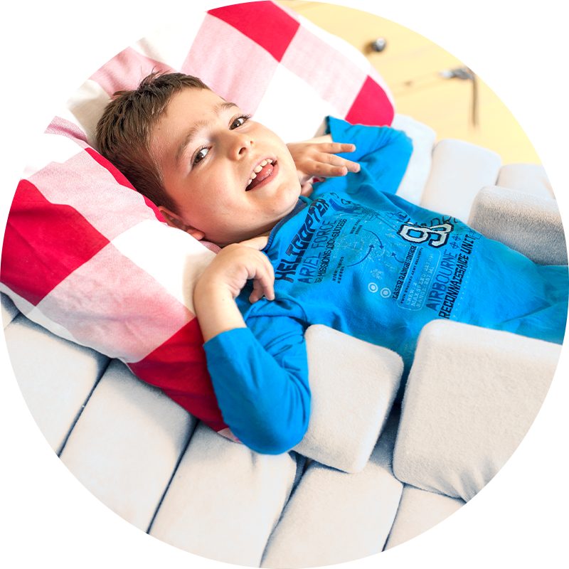 Postural Management at Home Sleeping example showing little boy using positioning equipment lying in a bed