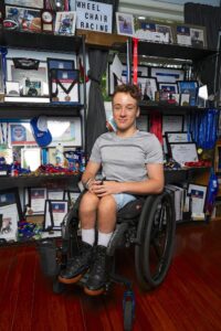 Spex ambassador Jaden Movold sitting in his Wheelchair in front of all his trophies.