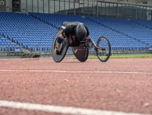 Jaden Mobvold in the middle of a wheelchair race, on an outdoor track.